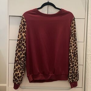 Maroon sweatshirt with leopard print sleeves.